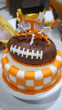 a football themed cake with orange and white checkered icing on it's edges