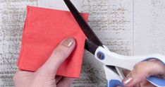 someone using scissors to cut paper on a piece of cloth