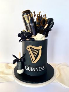 a cake decorated with black and gold items on top of a white table cloth covered table