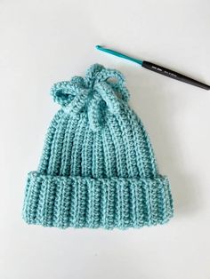 a knitted hat with a crochet knot on it next to a paintbrush