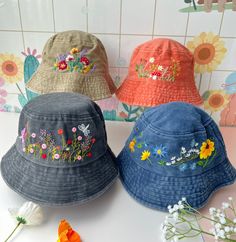 three hats with embroidered flowers on them sitting next to each other in front of a tiled wall