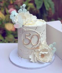 a white cake with flowers and the number 50 on it's side sitting on a table