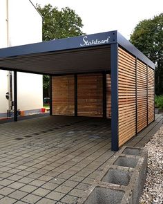 an outdoor covered parking lot with wood slats on the sides and brick pavers around it