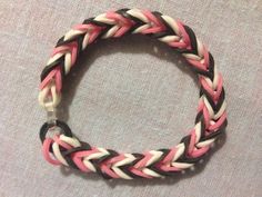 a pink, white and black braided bracelet sitting on top of a gray cloth