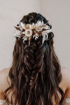 the back of a woman's head with long hair and flowers in her hair