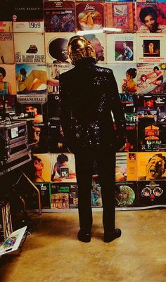 there is a man that is standing in front of the wall with records on it