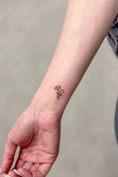 a small flower tattoo on the left wrist is shown in black ink, and it looks like