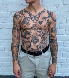 a man with tattoos standing in front of a brick wall