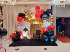 a casino themed birthday party with balloons, cards and poker suits on the stage set up