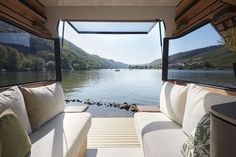 the inside of a boat with white couches and pillows on it's side