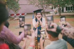 a group of people taking pictures with their cell phones and graduation caps on them,