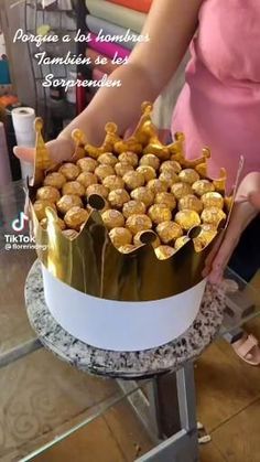 a woman is decorating a cake with gold decorations on it's top and sides