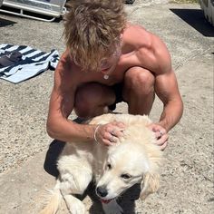 a shirtless man is petting a dog on the beach with his arm around him