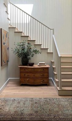 an entry way with stairs and a plant on the table