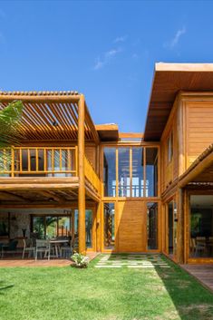 a large wooden house sitting on top of a lush green field next to a palm tree