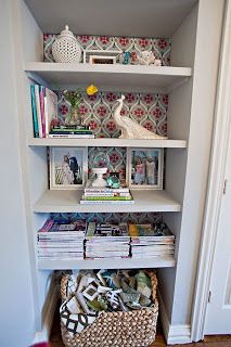 a white book shelf filled with lots of books next to a wallpaper covered door