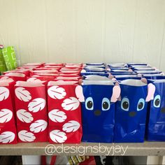 several blue and red bags with faces on them sitting on a table in front of other boxes