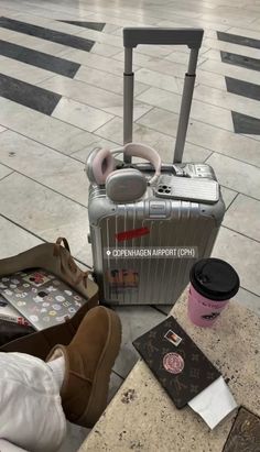 an aluminum suitcase sitting on the ground next to some shoes and other items in front of it