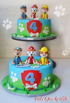 two tiered birthday cake with paw patrol figures on top and paw prints on the bottom