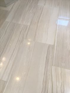 a bathroom with white marble flooring and light colored tiles on the walls, along with a toilet