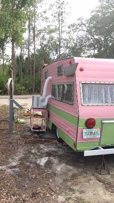 an old pink and green camper parked on the side of a road next to trees