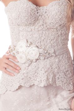 a woman in a wedding dress with a flower on her belt and an embellished brooch