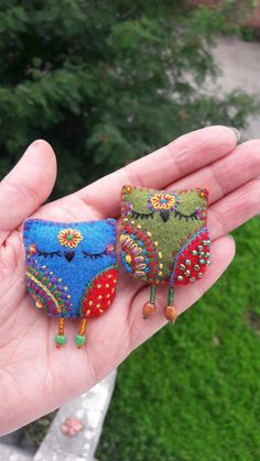 two small embroidered owl brooches are in someone's hand