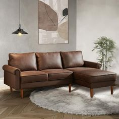 a brown leather couch sitting on top of a wooden floor next to a white rug