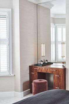 a bedroom with a large mirror, vanity and stool in it's center area