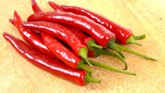 several red peppers on a wooden cutting board