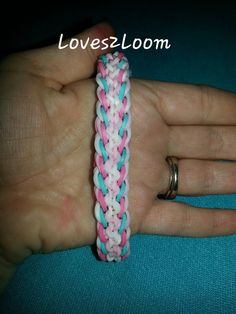 a hand holding a pink, white and blue braided bracelet