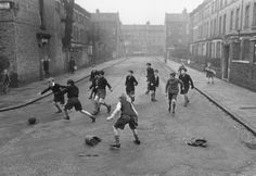 a group of young boys playing soccer in an alleyway with old brick buildings on either side