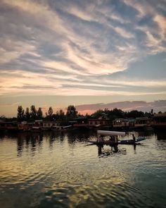 a boat floating on top of a lake under a cloudy sky