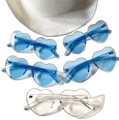 four pairs of sunglasses and a hat on top of a white surface with blue tinted lenses