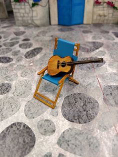 a miniature guitar sitting on top of a blue chair