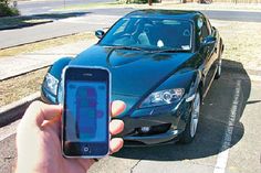 a person holding up a cell phone in front of a car with the number plate on it