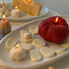 two plates with cheese and tomatoes on them, one has a candle in the middle