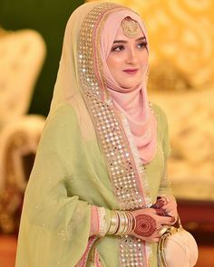 a woman in a green and pink outfit with jewelry on her head is smiling at the camera