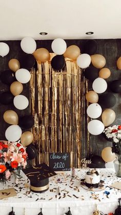 a table topped with lots of balloons and confetti on top of it next to a wall