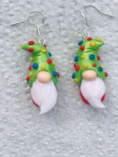 a pair of green and red earrings with white frosty snowman's head