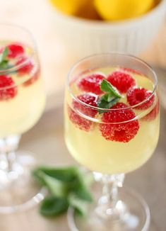 two glasses filled with lemonade and raspberries