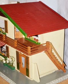 a doll house with a red roof and green shutters on the second story balcony