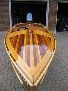 a wooden boat sitting in front of a garage