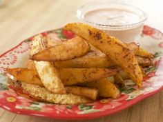 some french fries on a red and white plate next to a small bowl of ranch dressing