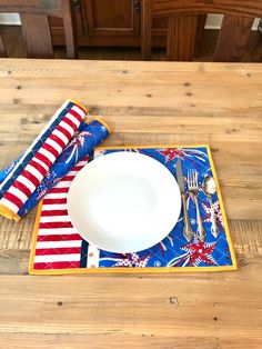 a place setting on a wooden table with patriotic napkins and fork, knife and spoon