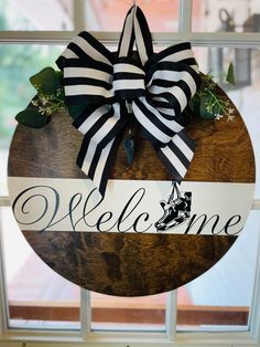 a welcome sign hanging on the side of a window sill with a ribbon attached to it