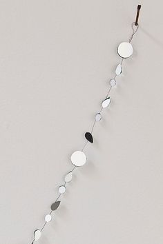 a long metal string with circles hanging from it's end on a white wall