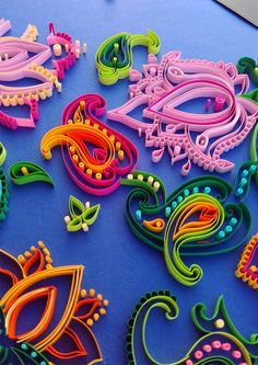 colorful paper quillings laid out on a blue surface