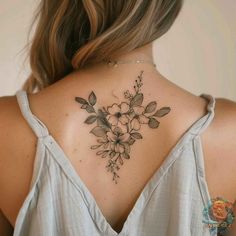 the back of a woman's neck with flowers and leaves tattooed on her chest