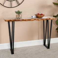 a wooden table with black metal legs and a bowl of fruit on the plate next to it